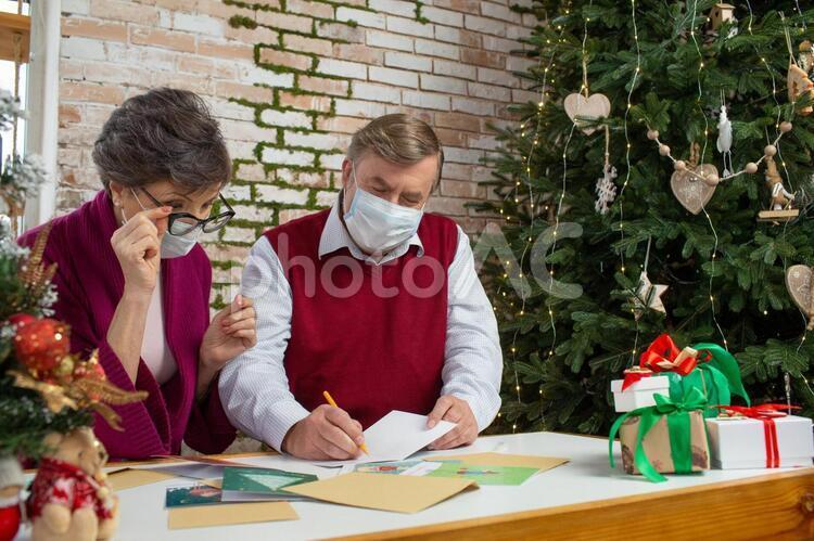 Elderly couple writing a Christmas card, after corona, with corona, old couple, JPG